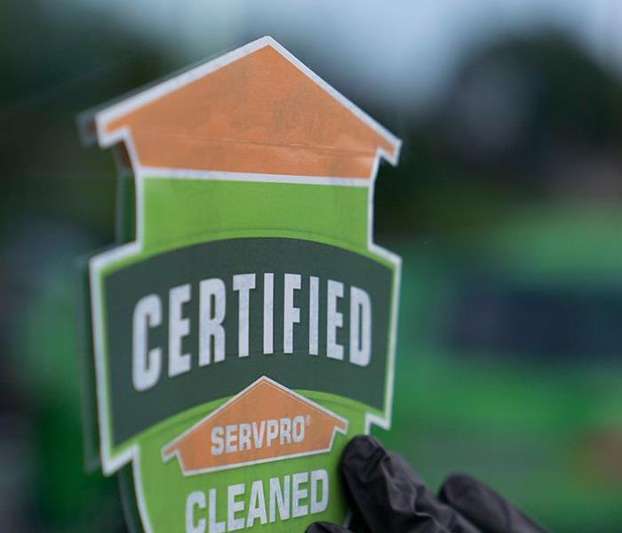 Certified: SERVPRO Cleaned (CSC) being placed on window with gloved-hand